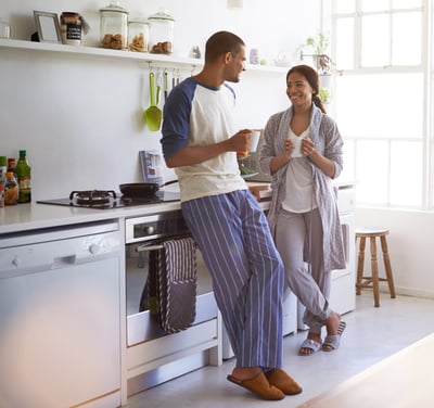 Smiling couple drinking coffee in kitchen protected by Tend home warranty.